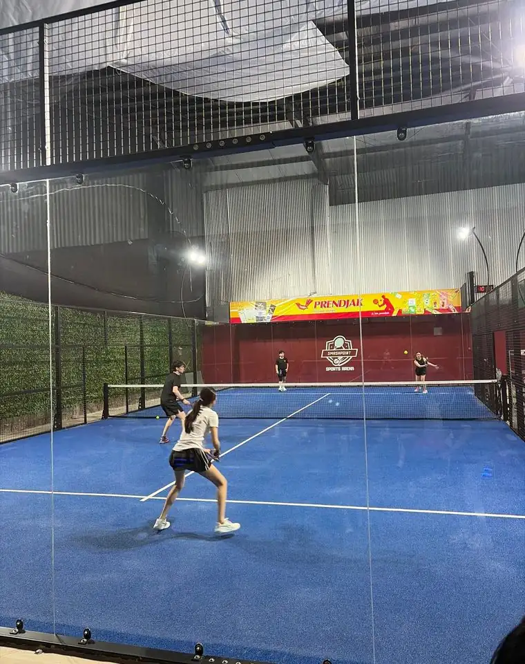 Players rallying on a blue padel court