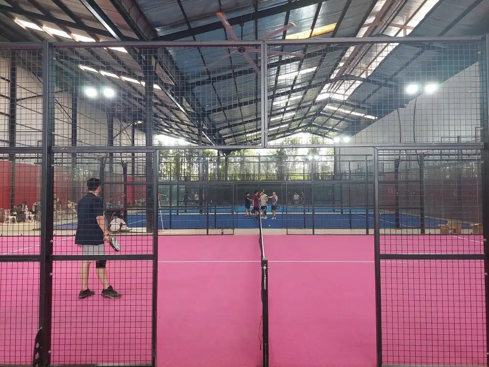 Hot-pink padel court under the steel roof